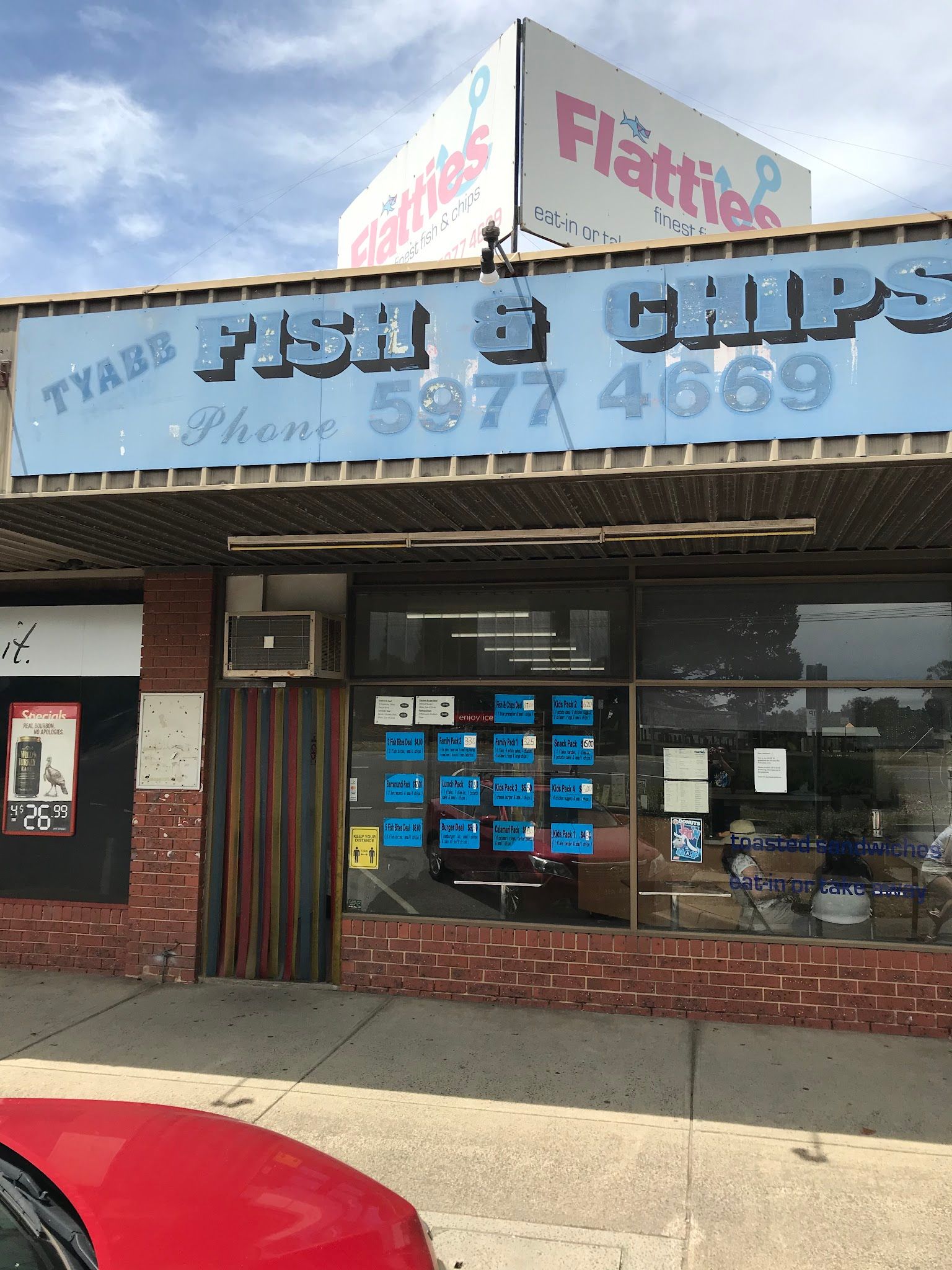 Flatties Fish and Chips storefront with large blue sign and colourful striped door columns