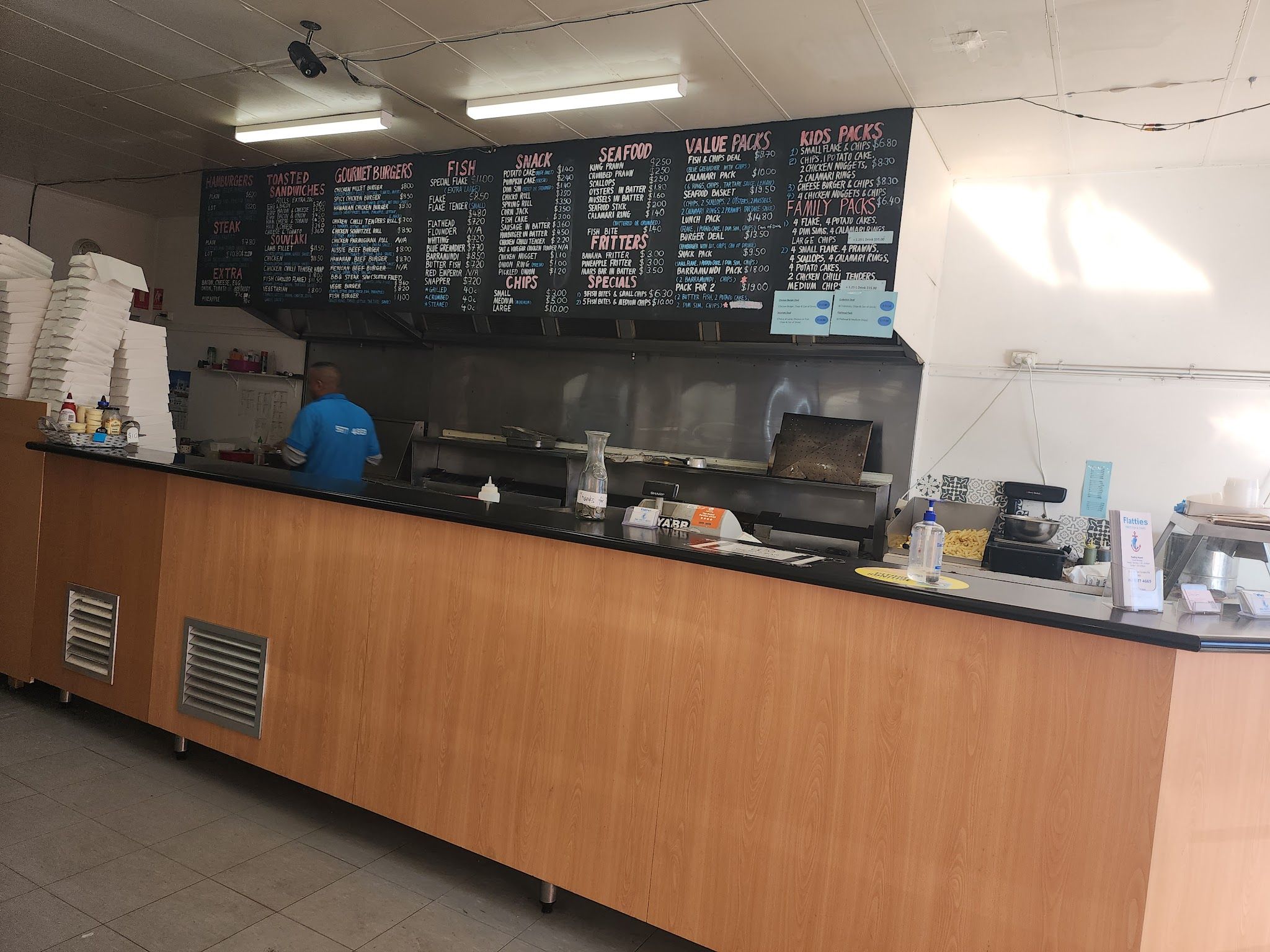 Flatties service counter with large handwritten chalkboard menu and staff member working