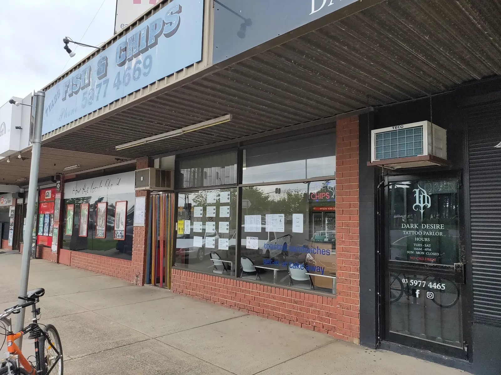 Wide exterior view of Flatties Fish and Chips strip mall storefront with neighbouring businesses