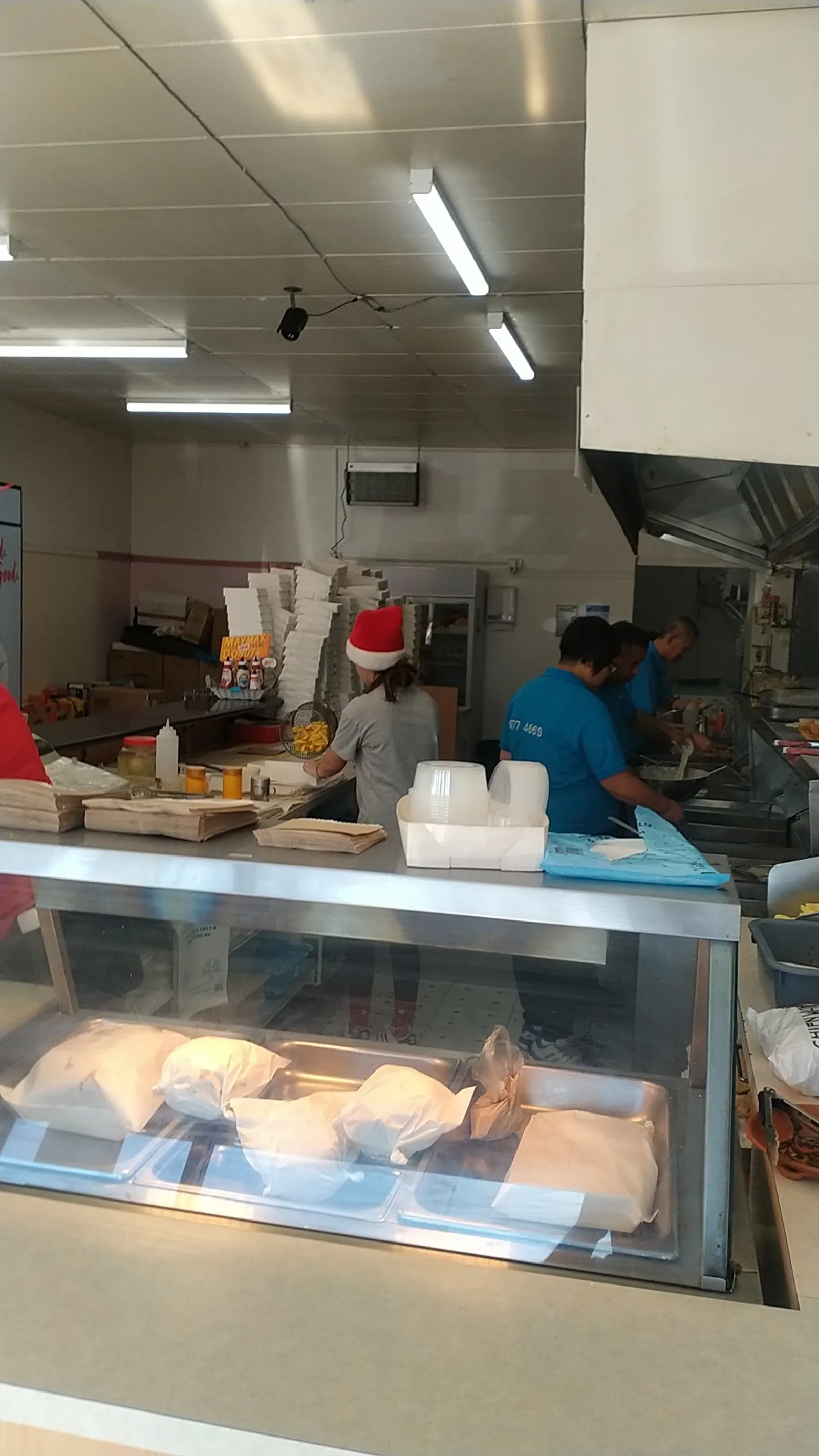 Three staff working in the Flatties kitchen, one wearing a Christmas hat, with stacked takeaway boxes